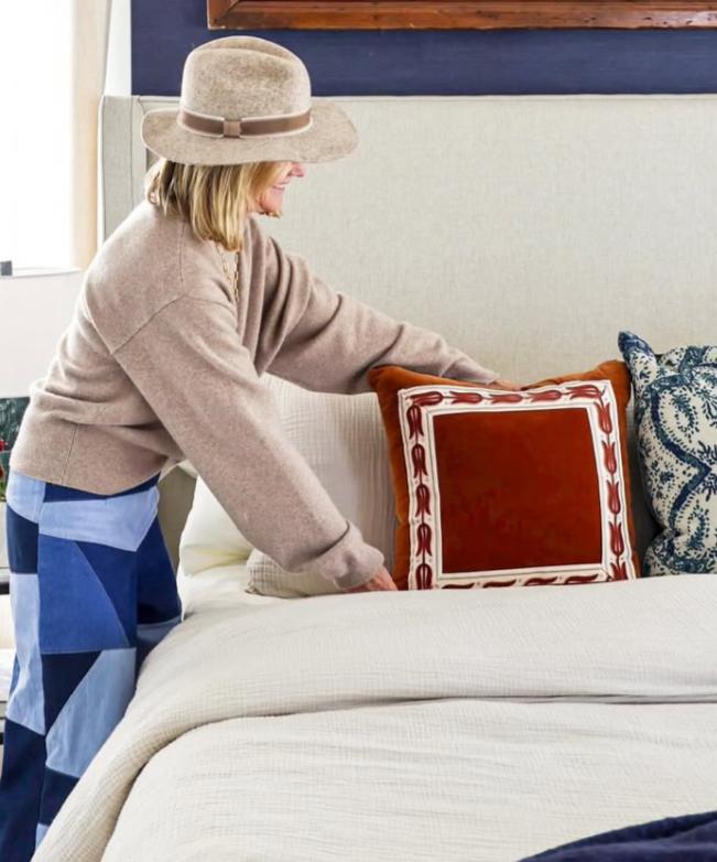 Stephanie Hunt arranging a red decorative pillow in the master bedroom