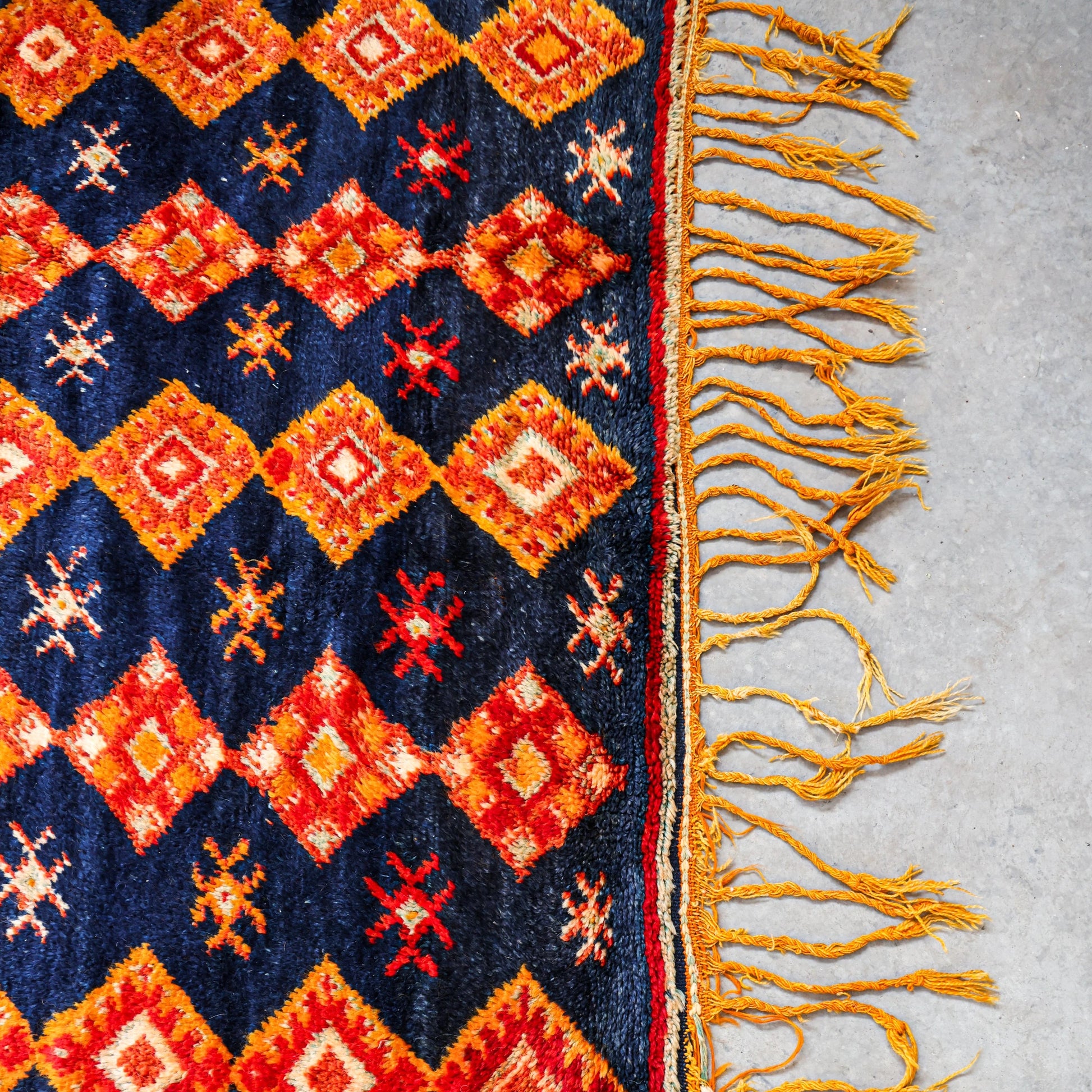 Close-up of a patterned rug with vibrant colors on a light gray floor.