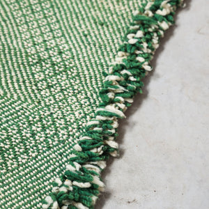 Close-up of a green and white woven fabric on a textured surface